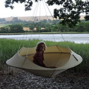 Hang-In-Out's natural white Lullio Cacoon hanging from a tree with a lady sitting in it